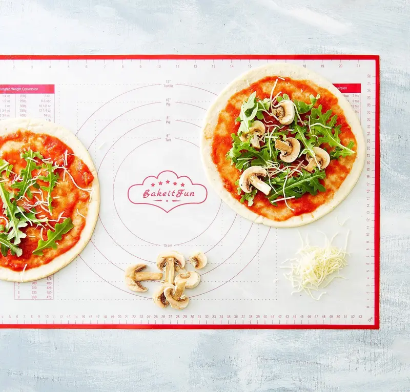 A red-bordered BakeitFun mat with printed circles, rulers, conversion charts and the cloud logo